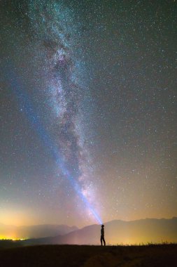 Yıldızlı gökyüzünün arka planında el feneri olan adam. Gece vakti.