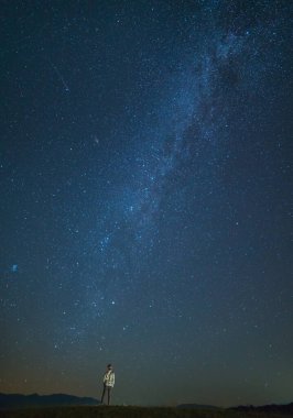 Adam yıldızlı gökyüzünün arka planında duruyor. Gece vakti.