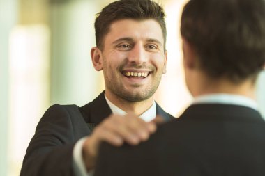 Mutlu adamlar ofiste omuzlarını tutarlar.