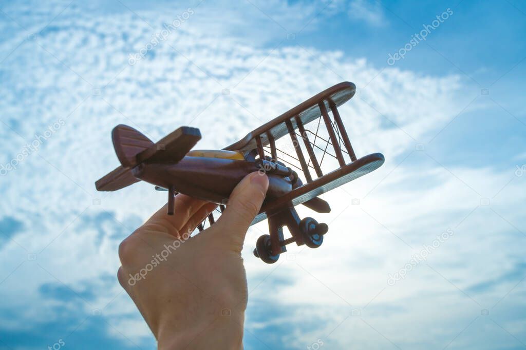 The hand with a wooden plane on the blue sky background