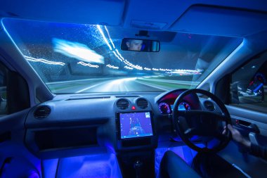 Adam şehirde GPS 'i olan bir araba kullanıyor. İyi akşamlar gece. Sol taraf trafiği
