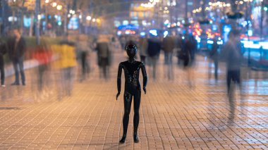 Manken caddede insanların arasında duruyor.