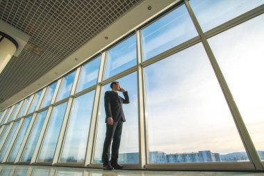 İş adamı telefonu panoramik pencerenin yanında.
