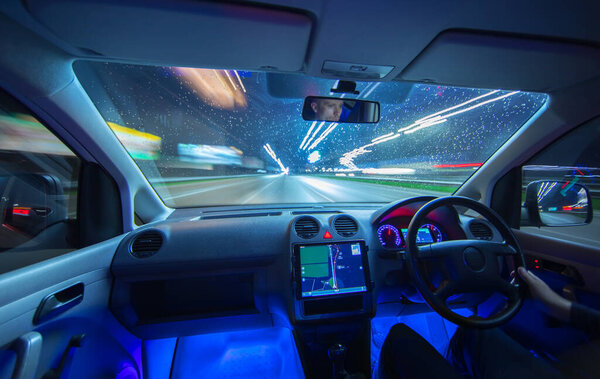 Мужчина водит машину с навигацией по дождевой дороге. Вечернее время
