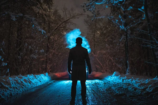 Der Mann Rauchte Auf Der Schneebedeckten Straße Dunklen Wald Abend lizenzfreie Stockfotos