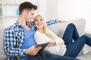 Mutlu adam tableti kanepede kadının yanında tutuyor.