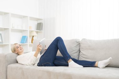 Mutlu kadın kanepeye uzandı ve bir tablet aldı.