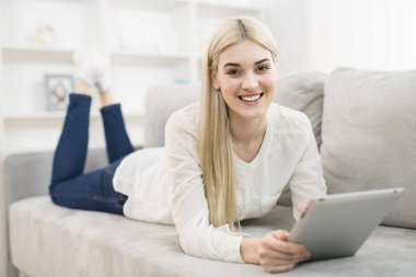 Mutlu kadın kanepeye uzandı ve bir tablet aldı.