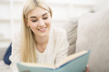Mutlu kadın kanepeye uzandı ve kitap okudu.