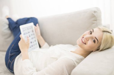 Tabletli mutlu kadın kanepede yatıyordu.