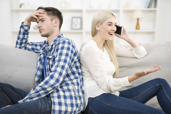 The happy woman phone near a man on the sofa
