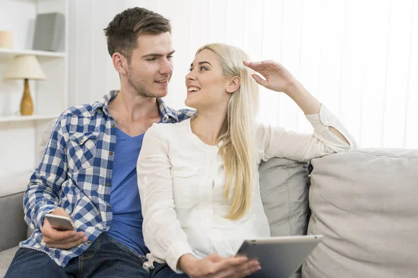 Casal Feliz Com Telefone Tablet Sentar Sofá — Fotografia de Stock