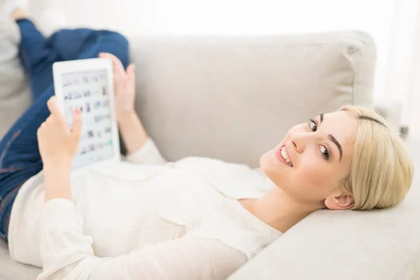 Mujer Feliz Con Una Tableta Yacía Sofá —  Fotos de Stock