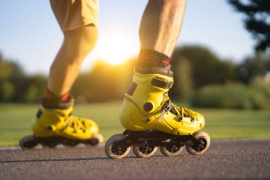 Günbatımı arka planında asfaltta paten kayan adam.