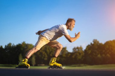 Yaşlı adam dışarıda paten kayıyor.