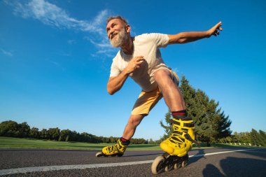 Yaşlı adam yolda paten kayıyor.