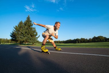 Yaşlı adam asfaltta paten kayıyor.