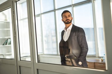 Ofis penceresinin yanında duran işadamı.