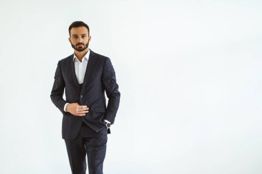 Beyaz arka planda duran takım elbiseli iş adamı.