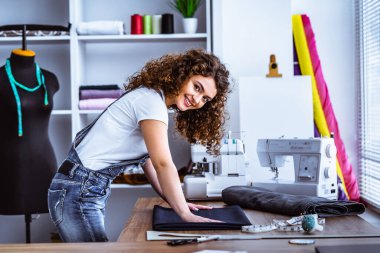 Mutlu kıvırcık kadın masaya dikiş diker