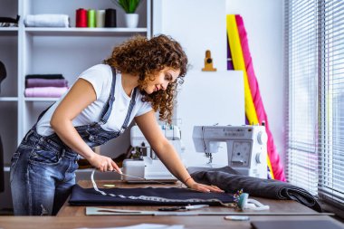 Güzel kadın masaya elbise dikiyor.