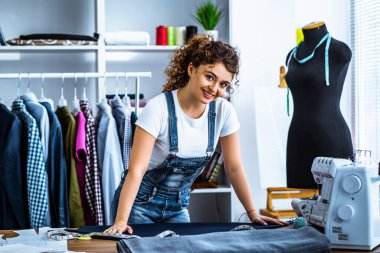 Dikiş makinesinin yanında çalışan mutlu terzi.