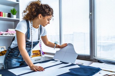 Genç terzi masaya bir elbise dikiyor.