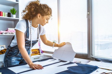 Genç terzi masaya bir elbise dikiyor.