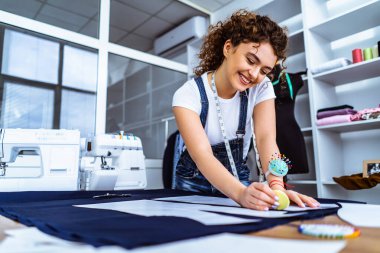Genç terzi masaya bir elbise dikiyor.