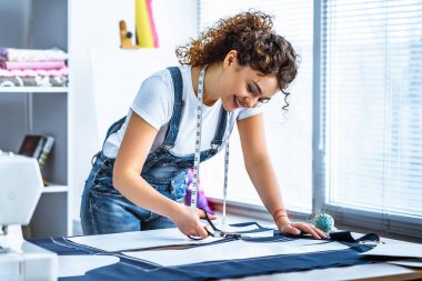 Şirin terzi masaya bir elbise dikiyor.