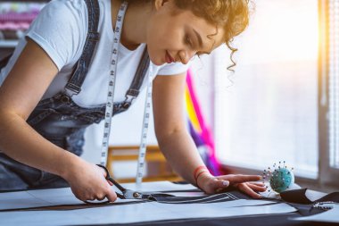 Güzel terzi masaya bir elbise dikiyor.
