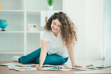 Masada oturan ve kağıda resim çizen kıvırcık kız.