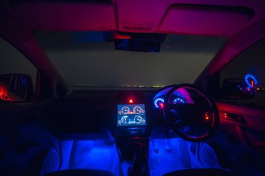 Mavi arka ışıklandırması olan modern bir arabanın içi. Akşam vakti.