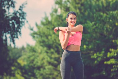 Sporcu kadın ağaçların arkasında duruyor.