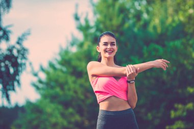 Mutlu sporcu kadın ağacın arka planında duruyor.