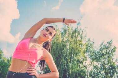 Ağaç arka planında gerinen sporcu kadın.