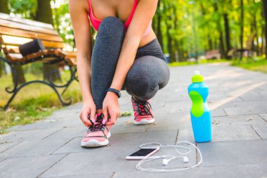 Kadın telefonun yanındaki ayakkabıları bağlıyor.