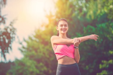 Mutlu sporcu kadın güneşli arka planda egzersiz yapıyor.