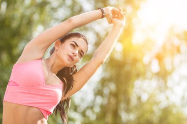 Sporcu kadın güneşli arka planda egzersiz yapıyor.