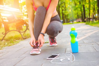 Parktaki kadın ayakkabılarını bağlıyor.