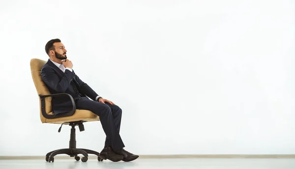 Zamyślony Mężczyzna Siedzący Fotelu Biurowym Białym Tle Ściany — Zdjęcie stockowe