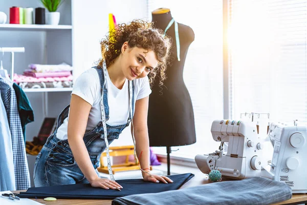 Dikiş makinesinin yanında çalışan mutlu terzi.