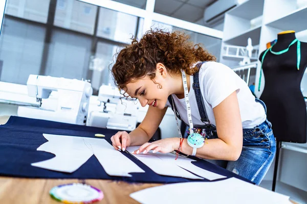 Şirin terzi masaya bir elbise dikiyor.