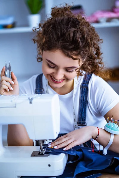 Dikiş makinesinin yanında çalışan mutlu kadın.