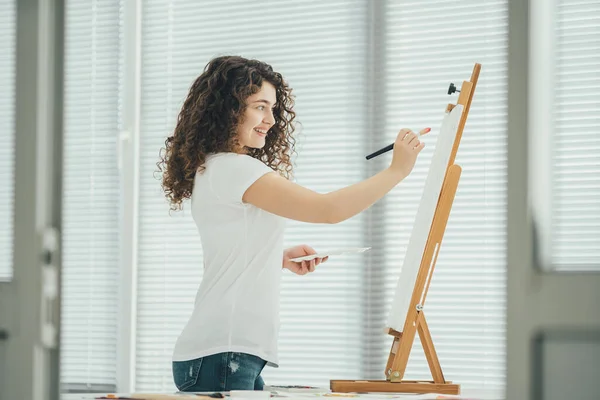 Ευτυχισμένη Γυναίκα Ζωγραφίζει Μια Εικόνα Στο Καβαλέτο — Φωτογραφία Αρχείου