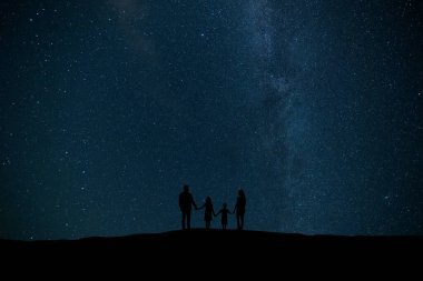 Yıldızlı bir gökyüzünün arka planında duran aile