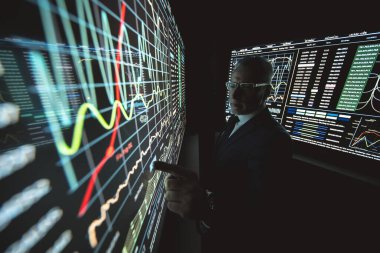 Karanlık laboratuardaki büyük sensör ekranında çalışan adam.