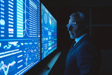 İşadamı karanlık ofisteki büyük sensör ekranında çalışıyor.