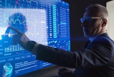 Karanlık odadaki büyük dijital ekranda çalışan adam.