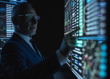 Karanlık odadaki büyük dijital ekranda çalışan adam.